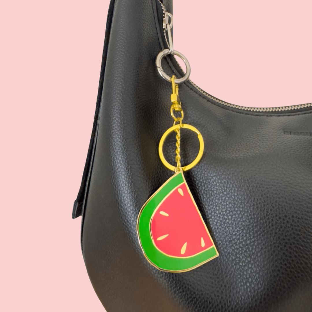 Black handbag with a watermelon keychain on a pink background
