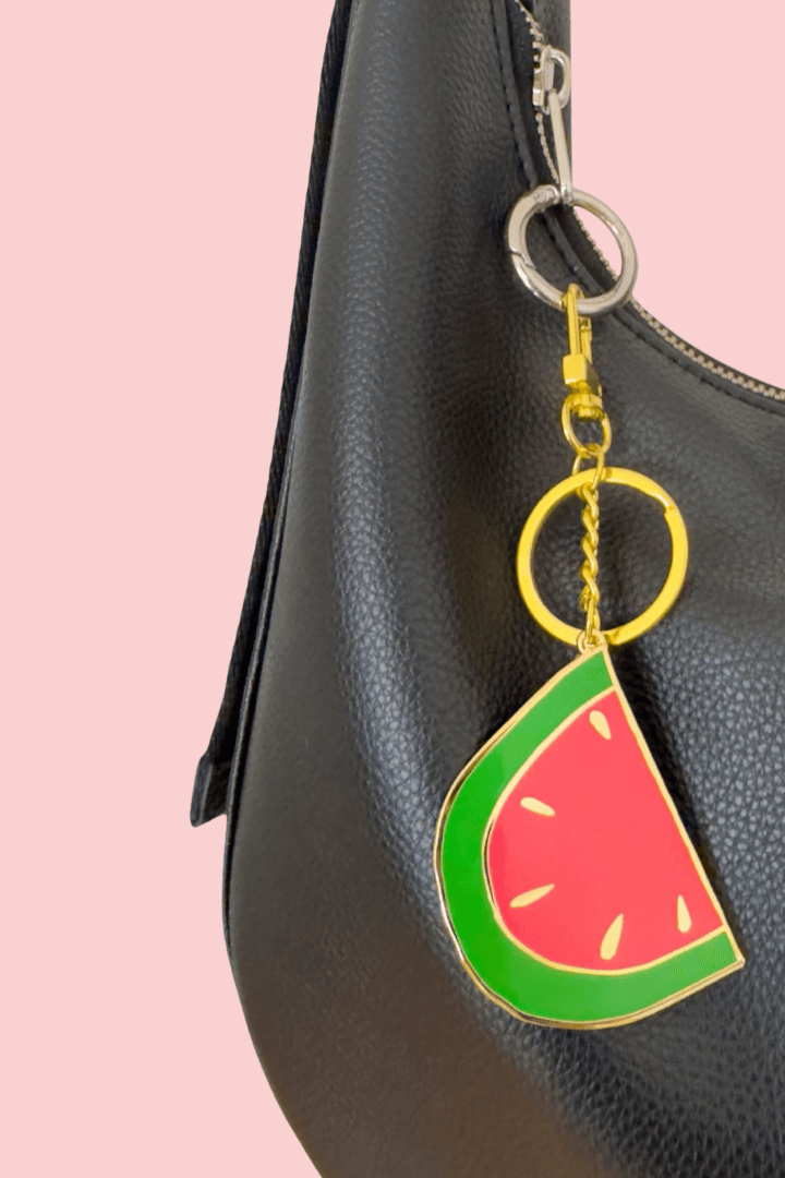 Black handbag with a watermelon keychain on a pink background