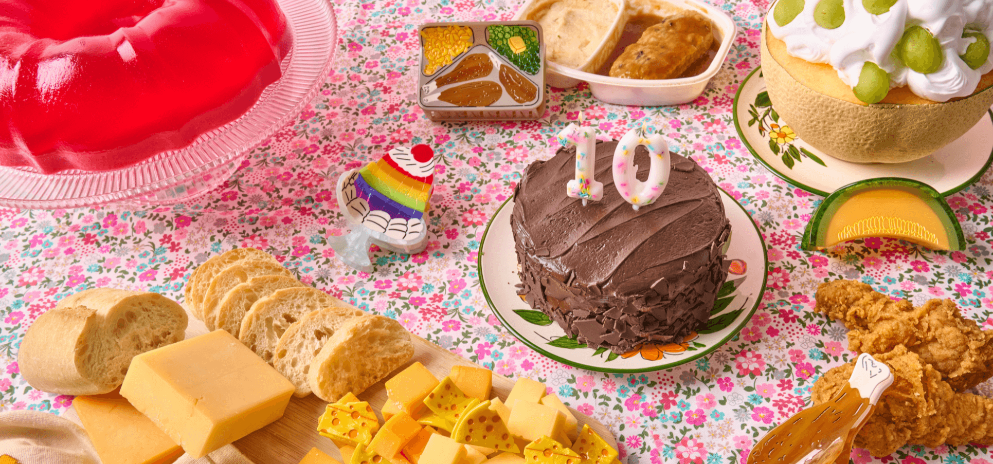 Assorted snacks and a chocolate cake on a floral tablecloth