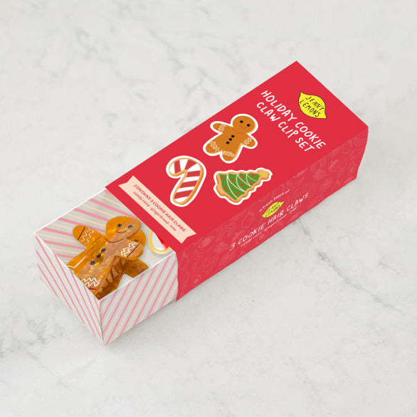 Red box with gingerbread man and candy cane designs on a white marble background